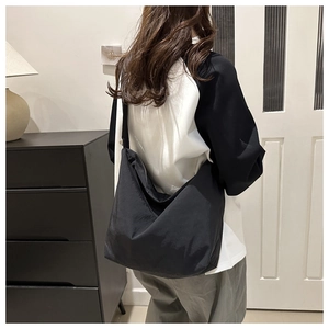 Detail der minimalistischen schwarzen Halbmond-Canvas-Tasche mit plissiertem Schultergurt