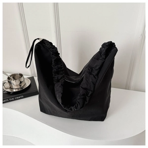 Detail of black canvas tote bag with drawstring pleated edges and minimalist strap