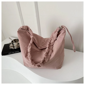 Close-up of pink oversized nylon tote bag with drawstring opening and pleated fabric texture