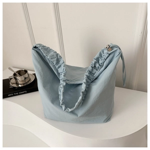 Close-up of light blue nylon tote bag featuring ruched handle detail in minimalist setting