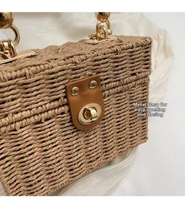 Detail of premium straw woven handbag featuring a brown leather strap and gold metal lock