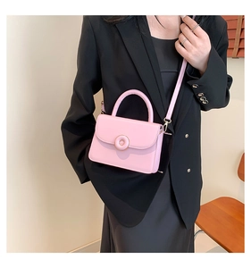 Detailed close-up of pink crossbody bag with metal ring closure on black blazer suit