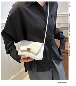 Close-up of a white rectangular crossbody bag with a sleek gold metal clasp detail