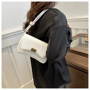Detail of white matte leather crossbody bag with decorative knots and golden metal clasp