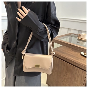 Close-up of beige leather shoulder bag featuring a unique wavy flap and gold buckle clasp