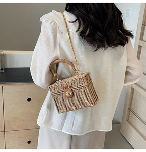 Detail of hand-woven beige straw box bag with leather flap and gold chain strap