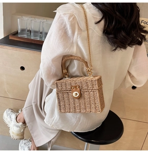 Detail of handmade straw square bag with gold chain strap and brown leather twist lock clasp