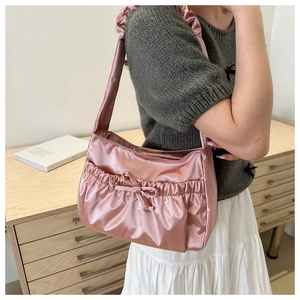 Detailed view of pink satin shoulder bag with ruffled edges and drawstring bow detail
