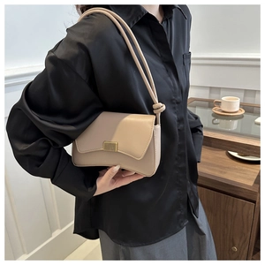 Detail of a chic beige underarm bag with a sleek gold metal buckle and knotted strap accents