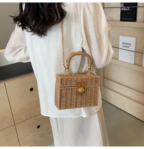 Detail of hand-woven box bag featuring a metallic swivel lock and elegant chain strap