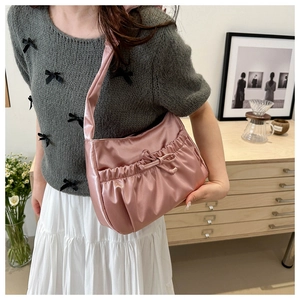 Detailed close-up of pink pleated satin shoulder bag featuring a stylish ribbon bow