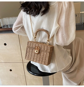 Detail of hand-woven straw crossbody bag with golden chain strap and metal clasp lock