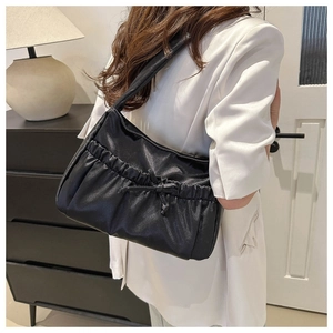 Fashionable black pleated nylon shoulder bag with bow detail shown on a model