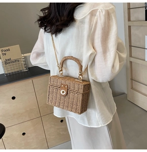 Detail of hand-woven rattan box bag with gold chain strap and metal clasp on model