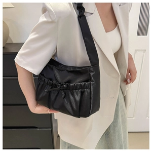 Close-up of black nylon shoulder bag featuring ruffled drawstring and bow detail