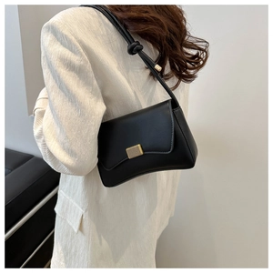 Detail of black matte shoulder bag featuring gold rectangular clasp and knotted strap detail