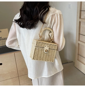 Detail of woven straw handbag with golden chain strap and metallic twist-lock closure