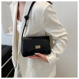 Detail of black leather shoulder bag with gold rectangular buckle and knotted strap
