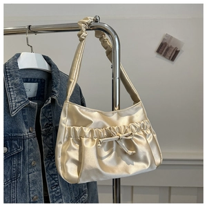 Detail of champagne satin pleated shoulder bag featuring a decorative bow and ruffled strap