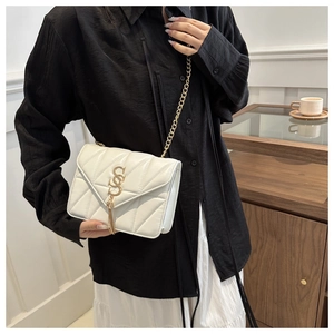 Détail d'un sac bandoulière matelassé blanc avec logo S doré et pompon élégant