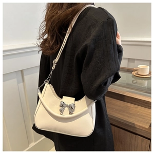 Détail d'un sac porté épaule demi-lune blanc crème avec une boucle métallique en nœud argenté