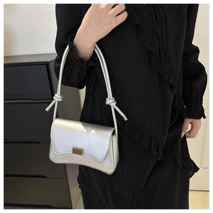 Detail of silver metallic crossbody bag with golden rectangular lock and knotted strap