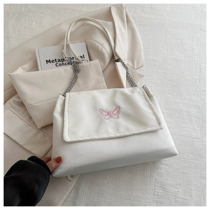 Détail du sac blanc avec broderie papillon rose et bandoulière en chaîne argentée