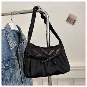 Detail of black pleated nylon shoulder bag with elegant satin finish and bow decoration