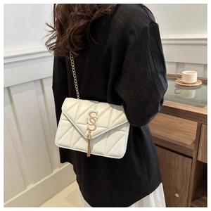 Detail of white quilted leather crossbody bag with gold V-pattern and tassel chain strap
