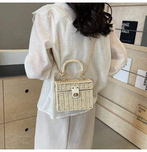 Detail of hand-woven cream box bag with gold metal clasp and chain strap on shoulder