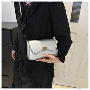 Close-up of silver crossbody bag with metallic gold buckle and pearlized leather texture