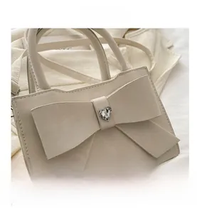 Détail du sac crème avec un grand nœud et une boucle en cristal en forme de cœur