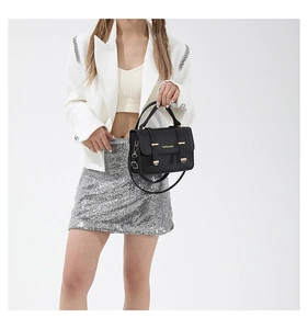Detail of black satchel bag with fashion lettering and metallic buckle on model with white blazer