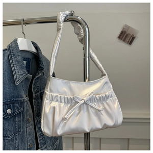 Detail of white pleated satin shoulder bag with decorative bow hanging on a hanger