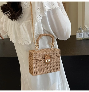 Close-up of woven rattan box bag with leather buckle and metal chain strap detail