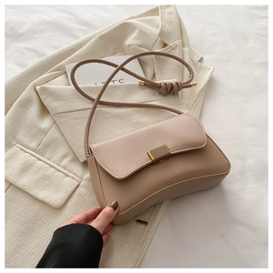 Detail of elegant beige-gold PU leather shoulder bag with crescent base and metal clasp