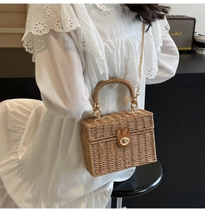 Detailed close-up of the natural straw texture and brown leather clasp on a handmade bag