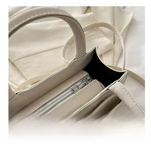 Détail de la fermeture éclair en métal argenté et de la doublure intérieure du sac blanc cassé