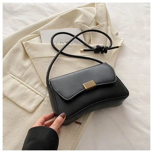 Detail of black crescent shoulder bag featuring gold buckle and thin knotted strap