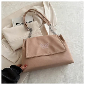 Détail du motif papillon brodé sur sac à bandoulière rose poudré avec chaîne argentée
