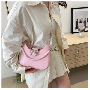 Détail du sac selle demi-lune rose avec boucle nœud argenté porté à l'épaule