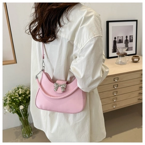 Détail d'un sac porté épaule rose avec boucle nœud argenté sur modèle dans un salon