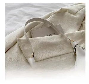 Detail of white crescent shoulder bag with golden metal ring and smooth faux leather