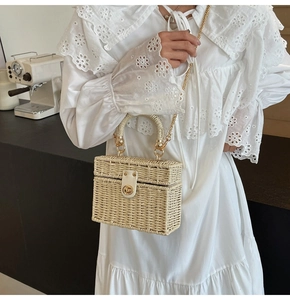 Detail of cream woven box bag with gold twist lock on a white lace dress