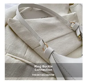 Detail of the golden metal ring connection on a white leather baguette shoulder bag