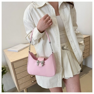 Détail du sac selle rose avec boucle nœud argentée et bandoulière en chaîne