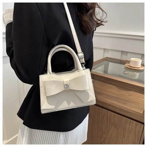 Détail du sac en cuir crème avec grand nœud et cristal en forme de cœur brillant
