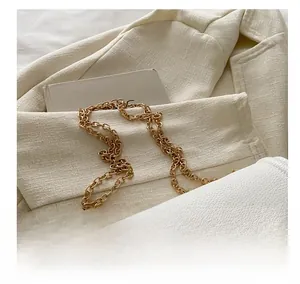 Gros plan du sac à main blanc en cuir grainé avec sa bandoulière en chaîne dorée