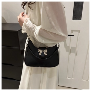 Détail du sac demi-lune noir avec boucle noeud argenté sur cuir mat lisse et élégant