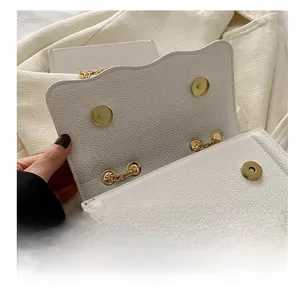 Gros plan sur le sac en cuir beige avec double fermoir magnétique doré et chaîne